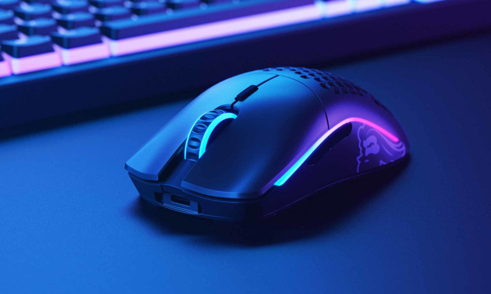 Czarna mysz komputerowa z podświetleniem RGB, widoczna na ciemnym tle. Obok znajduje się klawiatura z podobnym podświetleniem.