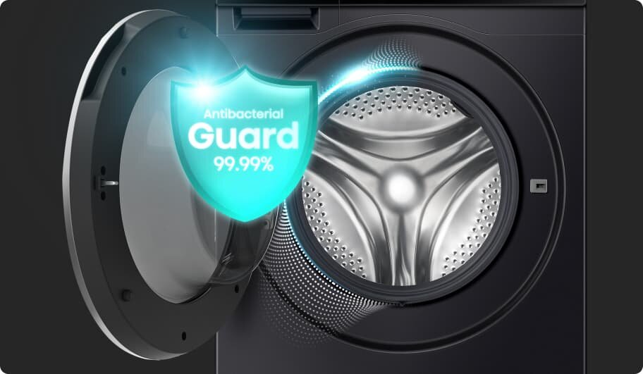 Obraz przedstawia otwartą pralkę z widocznym bębnem. Na drzwiach pralki znajduje się grafika z napisem \'Antibacterial Guard 99,99%\'.