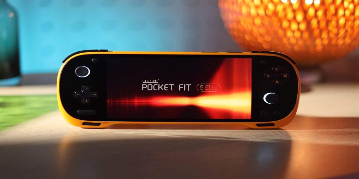 Na zdjęciu widoczna jest żółta konsola do gier z wyświetlaczem, na którym znajduje się napis \'ICONIC POCKET FIT 8 Elite\'. Konsola leży na stole, a w tle widać rozmyte światło lampy.