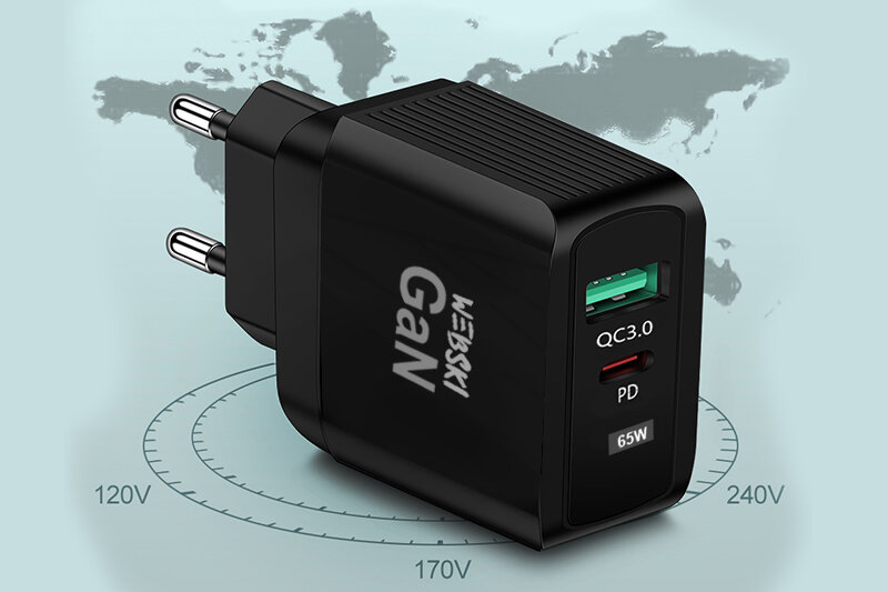 Czarna ładowarka sieciowa z dwoma portami USB, oznaczona jako GaN, z widocznymi napisami QC3.0, PD i 65W. W tle mapa świata z oznaczeniami napięć 120V, 170V, 240V.
