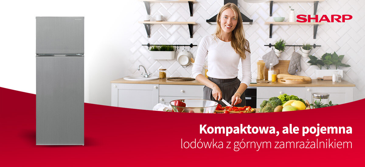 Kuchnia z białymi szafkami, na blacie stoją garnki i pojemniki. Po prawej stronie znajduje się lodówka w kolorze inox z logo SHARP i tekstem: \'Kompaktowa, ale pojemna lodówka z górnym zamrażalnikiem SHARP SJ-FTB01ITXLE-EU\'.
