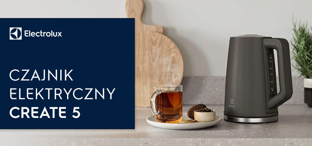 Na blacie kuchennym stoi czarny czajnik elektryczny obok szklanki z herbatą i ciastkiem. Po lewej stronie widoczny jest napis: \'Electrolux CZAJNIK ELEKTRYCZNY CREATE 5\'.