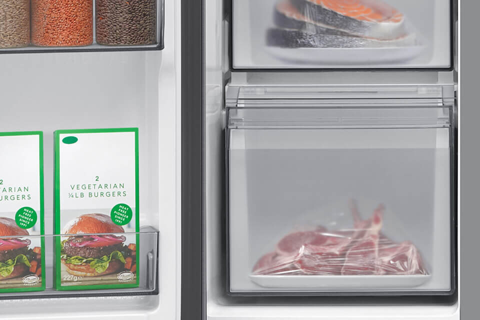 Wnętrze lodówki z widocznymi produktami spożywczymi, w tym opakowaniami z napisem \'2 VEGETARIAN 1/4LB BURGERS\'. W zamrażarce znajdują się zapakowane kawałki mięsa i ryby.