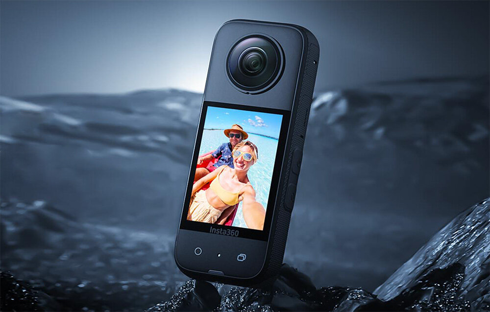 Kamera sferyczna z dużym obiektywem i wyświetlaczem, na którym widoczne jest zdjęcie dwóch osób. Na dole ekranu znajduje się napis \'Insta360\'.