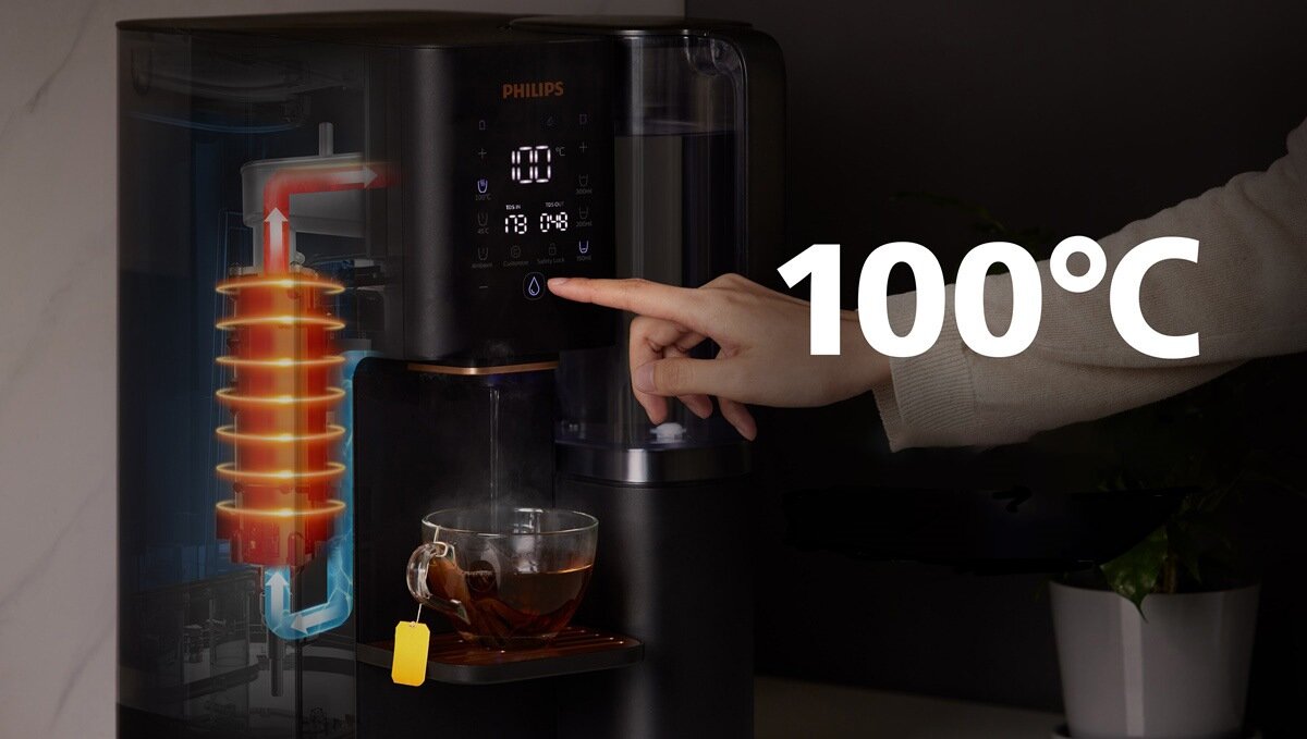Osoba dotyka panelu sterowania dyspensera do wody marki PHILIPS, na którym wyświetlana jest temperatura 100°C. Obok znajduje się filiżanka z herbatą, a na obrazie widoczny jest przekrój urządzenia z zaznaczonym procesem podgrzewania wody.
