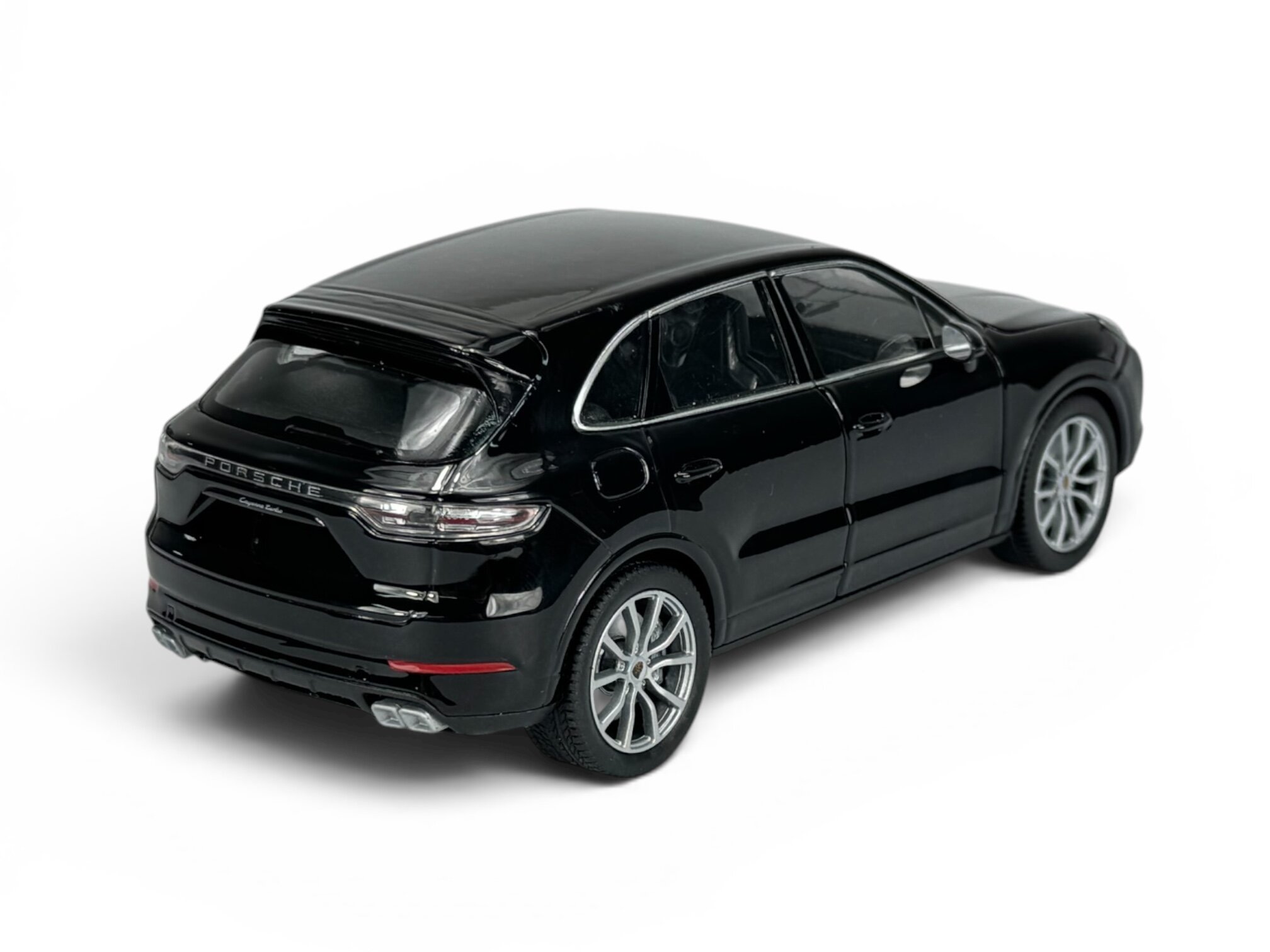 Czarny model samochodu w skali 1:24, przedstawiający SUV-a z detalami takimi jak reflektory i felgi. Na tylnej klapie widoczny jest napis \'PORSCHE\'.