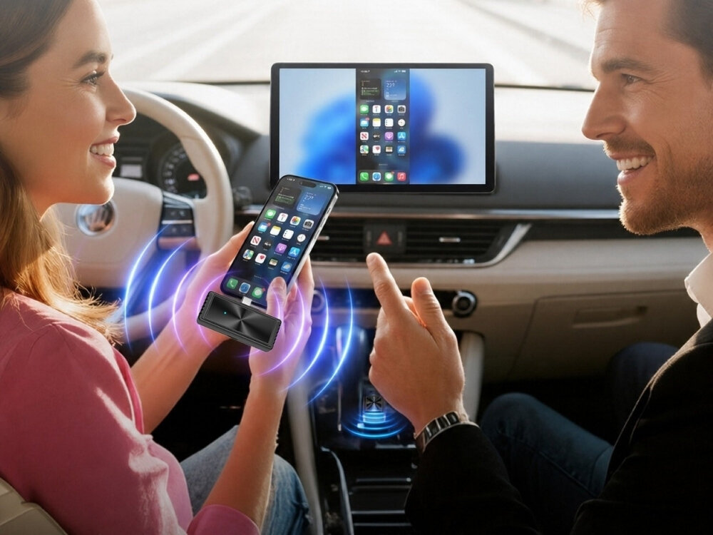 W samochodzie dwie osoby siedzą z przodu, jedna z nich trzyma smartfon z wyświetlonymi ikonami aplikacji. Na desce rozdzielczej znajduje się duży ekran, na którym również widać ikony aplikacji.