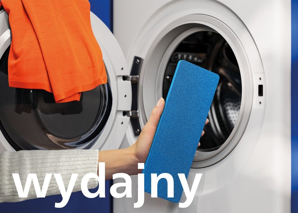 Osoba trzyma niebieski pad przed otwartą pralką, na której drzwiach wisi pomarańczowa tkanina. Na obrazie widoczny jest napis \'wydajny\'.