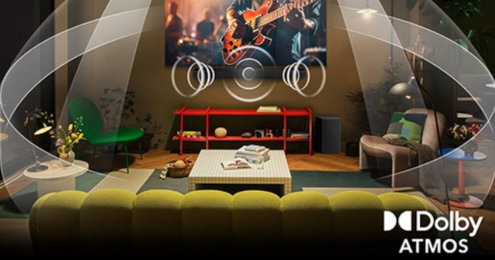 W salonie znajduje się telewizor wyświetlający koncert gitarowy, otoczony efektami dźwiękowymi Dolby Atmos. Na dole obrazu widoczne jest logo \'Dolby Atmos\'.