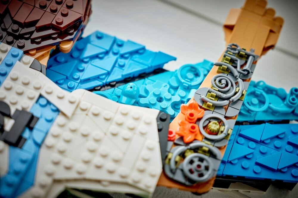Zbliżenie na zestaw klocków LEGO w różnych kolorach, w tym niebieskim, białym i brązowym, z widocznymi detalami w postaci okrągłych elementów i wzorów.
