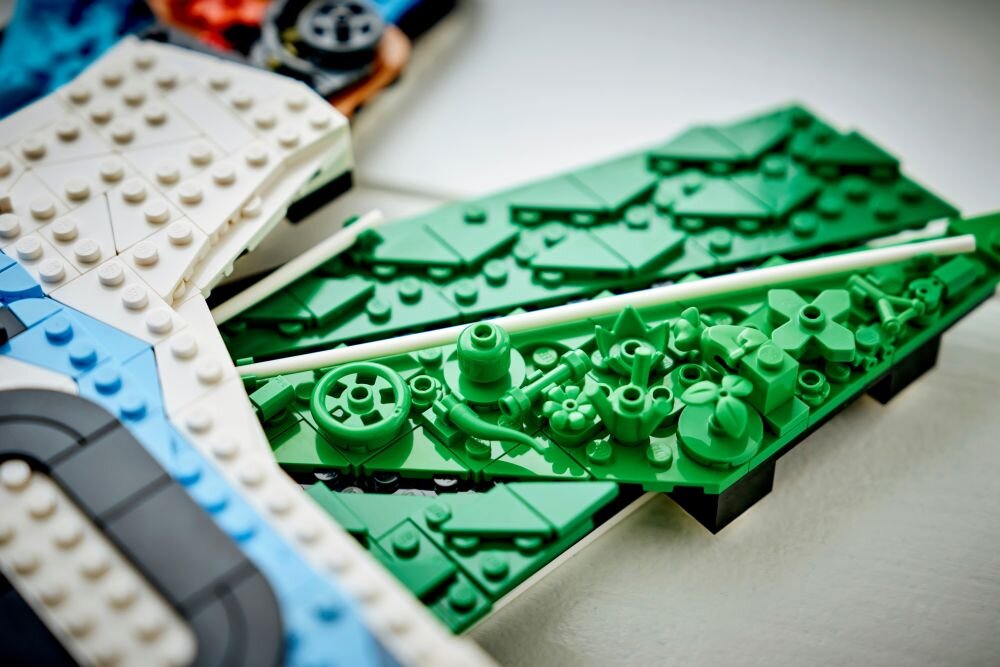 Zbliżenie na zestaw klocków LEGO w kolorach zielonym, białym i niebieskim, z widocznymi detalami i różnorodnymi kształtami elementów.