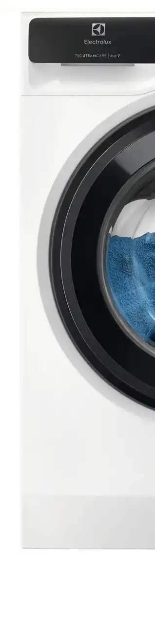 Fragment pralki z widocznym okrągłym oknem załadunkowym, w którym znajduje się niebieski ręcznik. Na górze widoczny jest napis \'Electrolux 700 SteamCare\'.