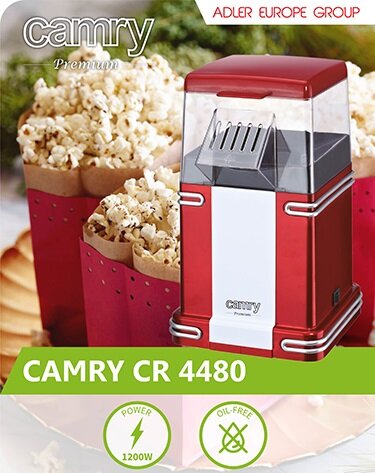 Czerwona maszyna do popcornu CAMRY CR 4480 z przezroczystą pokrywą, obok której znajdują się kubki z popcornem. Na obrazie widoczne są napisy: \'camry Premium\', \'ADLER EUROPE GROUP\', \'CAMRY CR 4480\', \'POWER 1200W\', \'OIL-FREE\'.