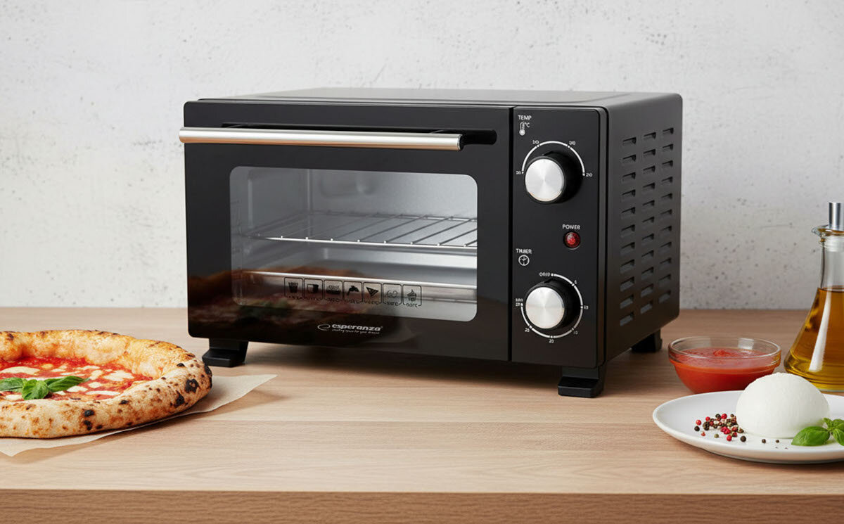 Czarny mini piekarnik z dwoma pokrętłami i szklanymi drzwiczkami, obok którego znajduje się pizza oraz talerz z mozzarellą i przyprawami. Na piekarniku widoczne jest logo \'ESPERANZA\'.