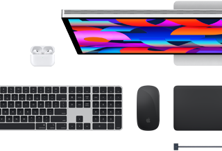 Na obrazie widoczny jest laptop z kolorowym ekranem, klawiatura, myszka, touchpad oraz słuchawki bezprzewodowe. Logo producenta to nadgryzione jabłko.