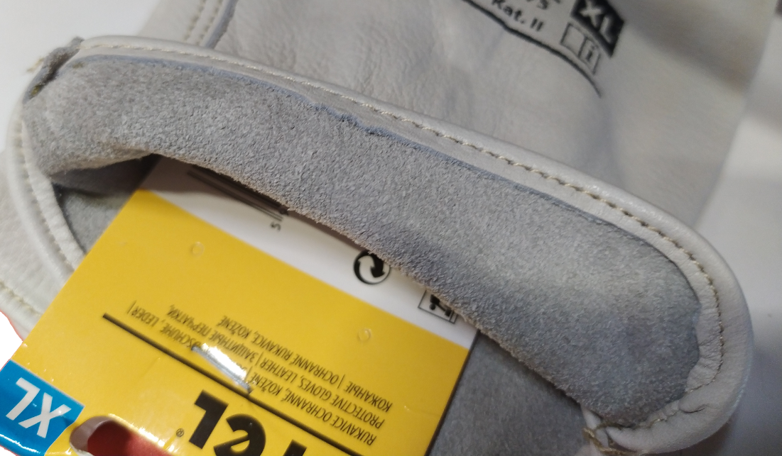 Zbliżenie na skórzaną rękawicę roboczą z widoczną metką w kolorze żółtym z napisem \'12 Par\' oraz oznaczeniem rozmiaru \'7XL\'.