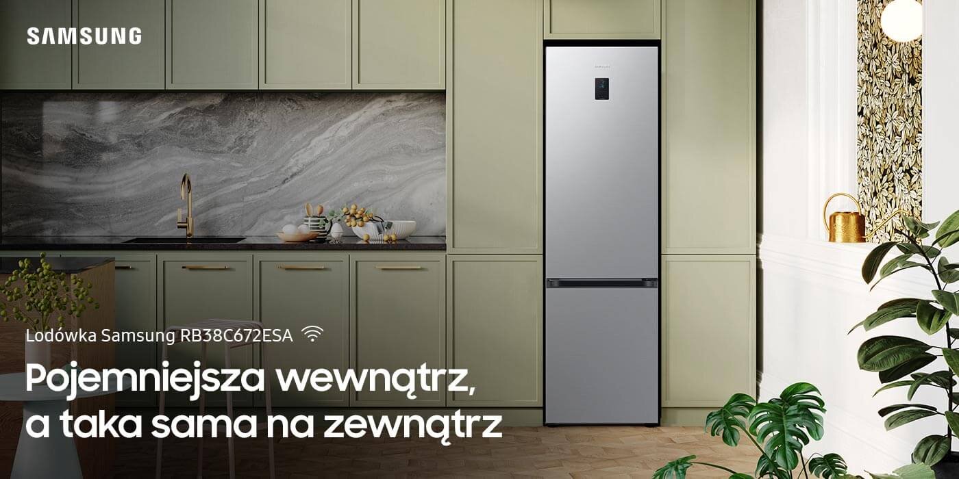 Lodówka Samsung Grand+ RB38C672ESA z zewnętrznym wyświetlaczem pokazana w nowocześnie urządzonej kuchni Obraz przedstawia kuchnię z lodówką Samsung RB38C672ESA w metalicznym grafitowym kolorze, umieszczoną pomiędzy szafkami. Na obrazie widoczny jest tekst: \'Lodówka Samsung RB38C672ESA Pojemniejsza wewnątrz, a taka sama na zewnątrz\'.