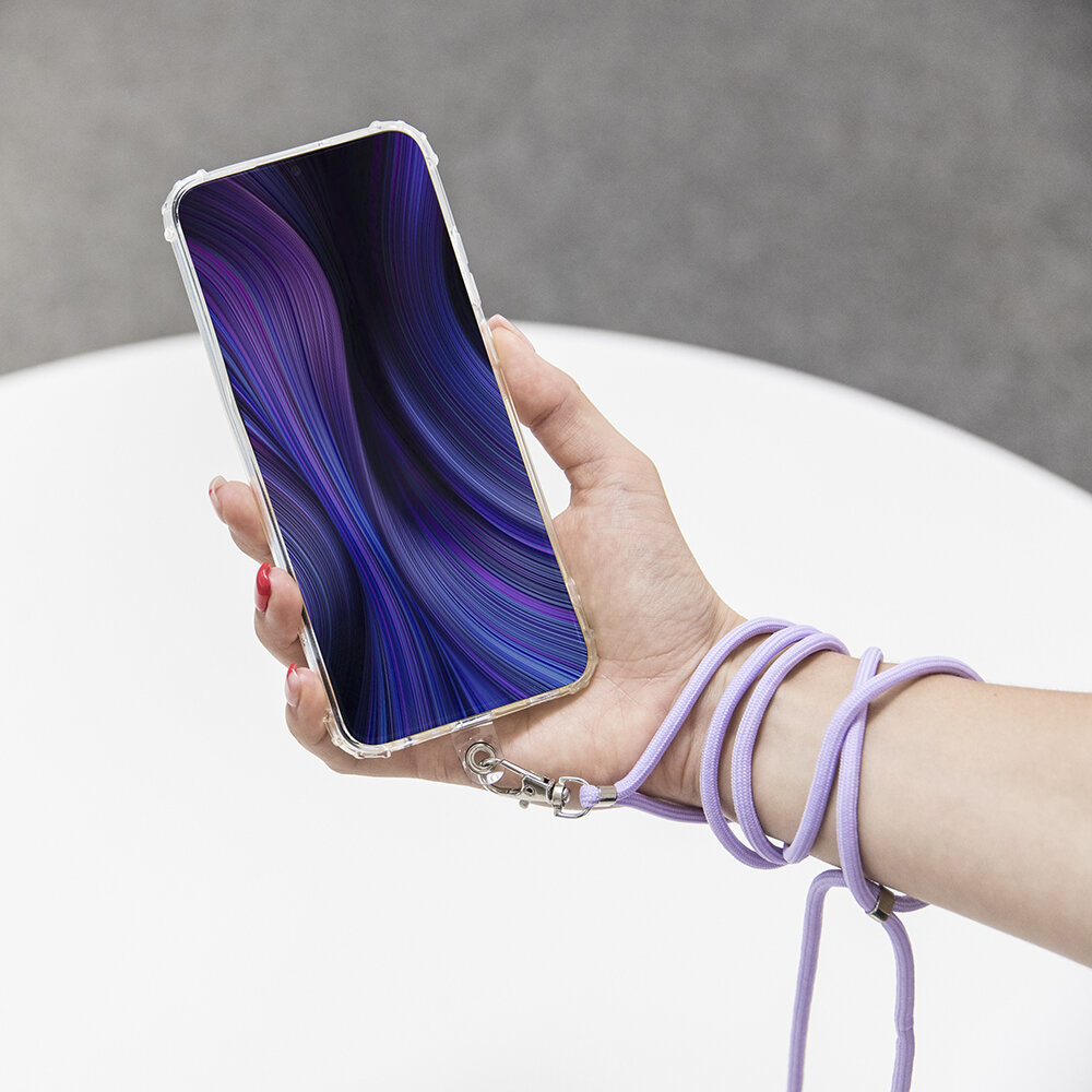 Osoba trzyma telefon z abstrakcyjną, fioletowo-niebieską grafiką na ekranie. Telefon jest przymocowany do fioletowej tasiemki owiniętej wokół nadgarstka.