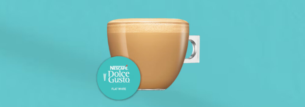 Na tle w kolorze turkusowym znajduje się filiżanka z kawą o jasnobrązowym kolorze i pianką na wierzchu. Obok filiżanki widoczna jest kapsułka z napisem \'NESCAFÉ Dolce Gusto Flat White\'.