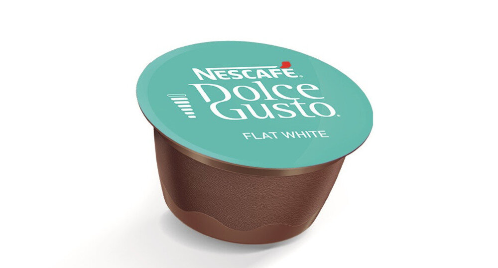 Kapsułka do kawy z brązowym korpusem i turkusowym wieczkiem z napisem \'NESCAFE Dolce Gusto FLAT WHITE\'.
