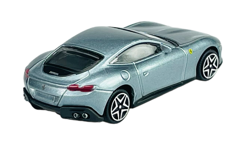 Srebrny model samochodu sportowego w skali 1:43 z widocznymi detalami, takimi jak logo producenta i charakterystyczne felgi. Samochód ma elegancki, aerodynamiczny kształt i podwójny wydech.