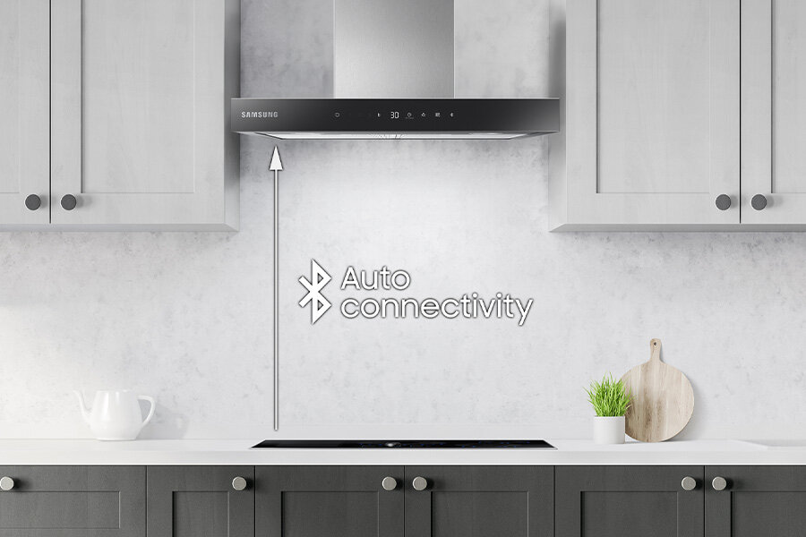 Kuchnia z zamontowanym okapem marki Samsung nad płytą grzewczą. Na ścianie widoczny jest napis \'Auto connectivity\' z symbolem Bluetooth.