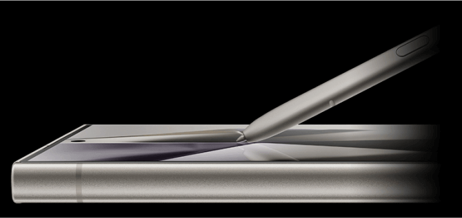 Obraz przedstawia smartfon z metaliczną obudową i rysikiem umieszczonym na ekranie. Urządzenie ma zaokrąglone krawędzie i widoczny przycisk na rysiku.