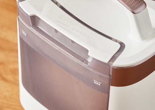 Zbliżenie na biało-brązowy pojemnik z uchwytem, z widocznym napisem \'MAX\'.