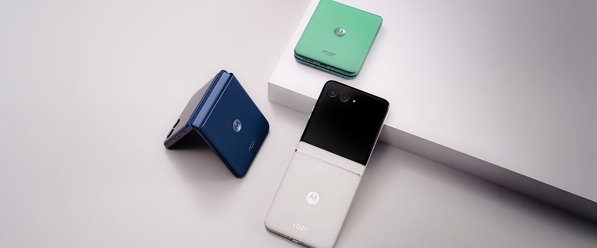 Na obrazie widoczne są trzy składane smartfony w różnych kolorach: granatowym, zielonym i srebrnym. Każdy z nich ma logo \'razr\' oraz charakterystyczne zgięcie na środku obudowy.