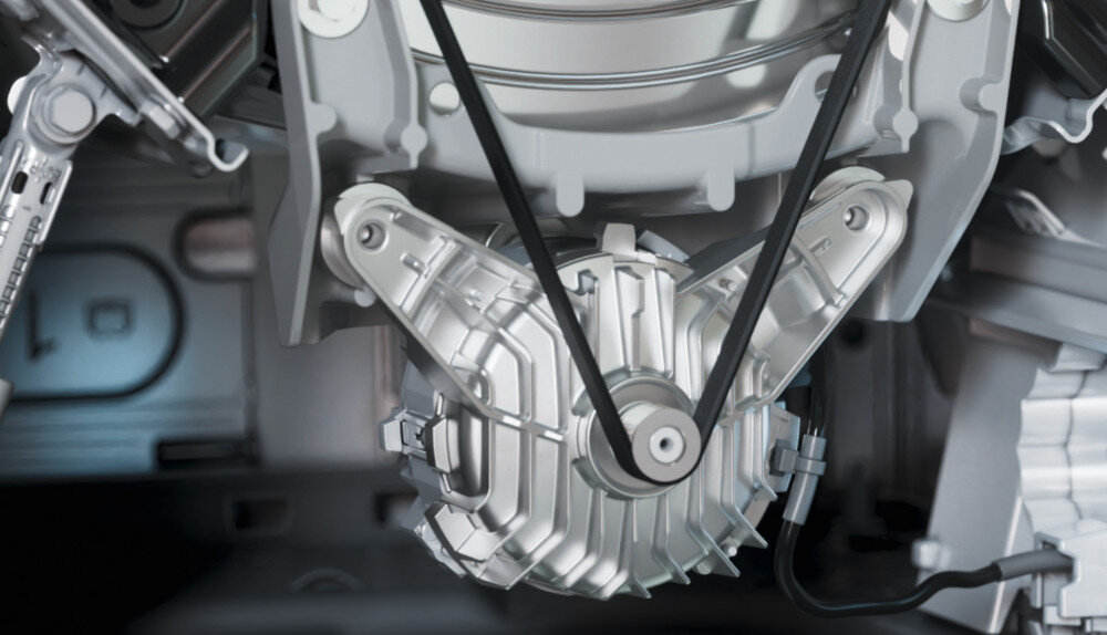 Zdjęcie przedstawia wnętrze pralki z widocznym mechanizmem napędowym i paskiem klinowym. Elementy są wykonane z metalu i plastiku, a całość ma srebrzysty kolor.