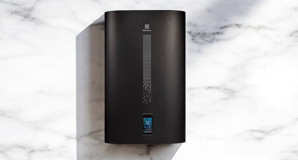 Czarny bojler elektryczny z logo Electrolux na górze i wyświetlaczem cyfrowym pokazującym temperaturę 52°C na dole. Urządzenie znajduje się na tle marmurowej powierzchni.