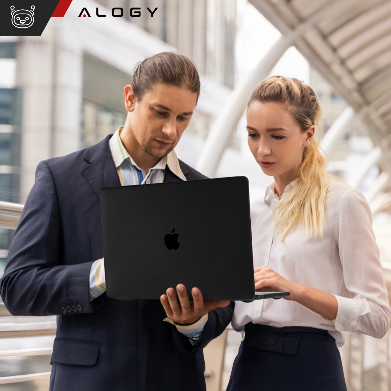 Dwie osoby trzymają laptopa z czarnym, matowym etui ochronnym. W lewym górnym rogu widoczne jest logo \'ALOGY\'.