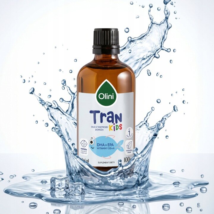 Butelka produktu Olini Tran Kids 100 ML z ciemnego szkła z czarną nakrętką, otoczona rozpryskującą się wodą. Na etykiecie widnieje napis: \'Olini Tran Kids, olej z wątroby dorsza, DHA + EPA, witaminy D3+A, suplement diety, 100 ml\'.