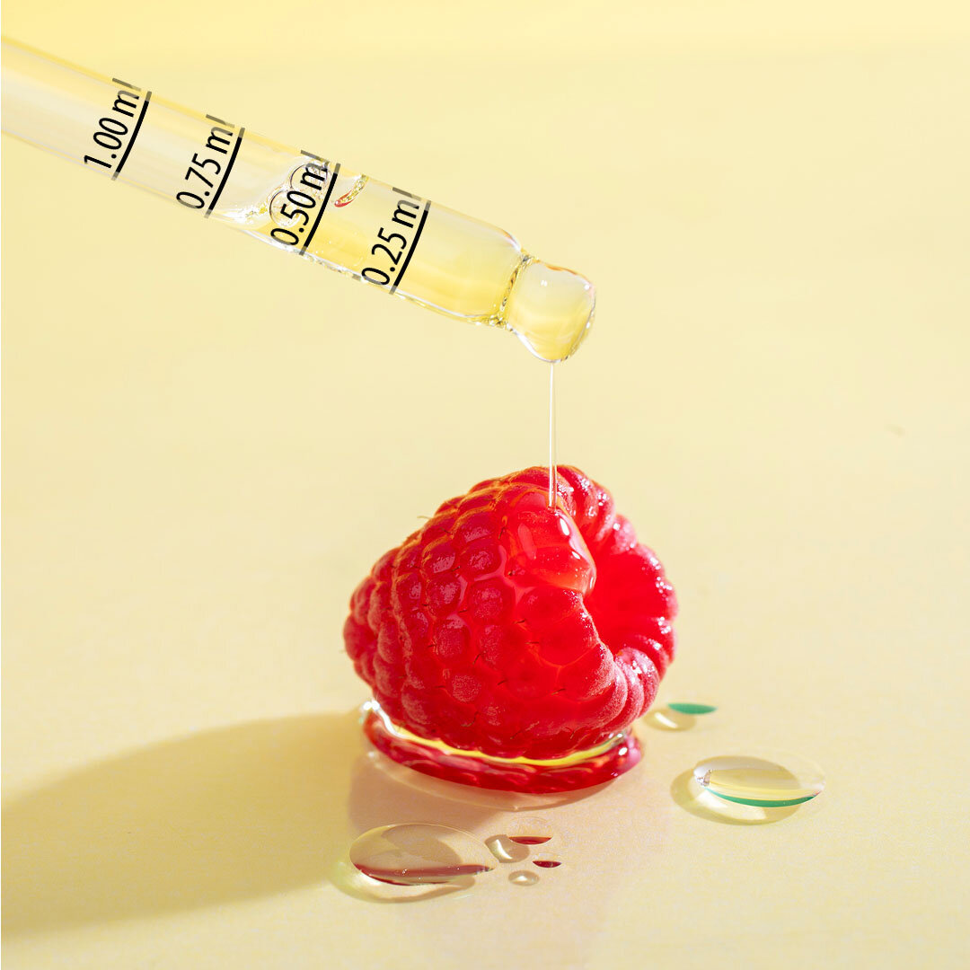 Pipeta z oznaczeniami 1.00 ml, 0.75 ml, 0.50 ml, 0.25 ml aplikuje przezroczysty płyn na malinę. Na jasnym tle widoczne są krople płynu.
