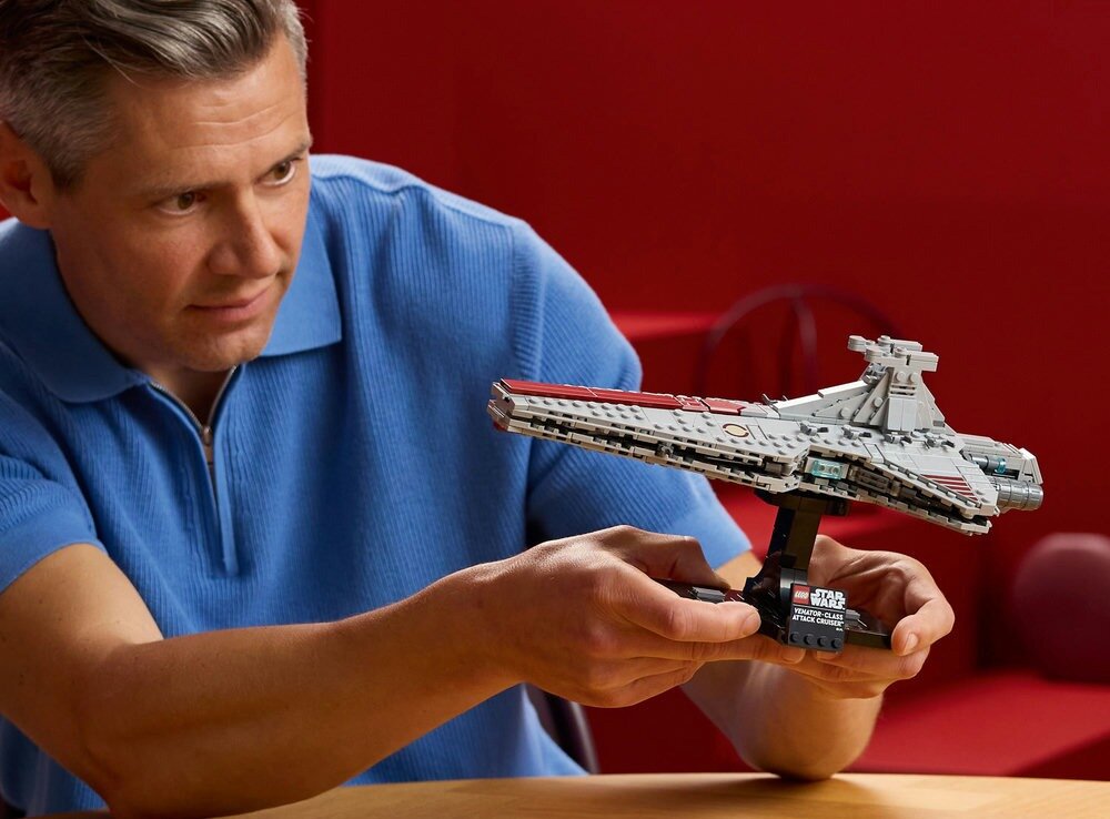 Osoba trzyma model LEGO przedstawiający krążownik szturmowy typu Venator z serii Star Wars. Na podstawce modelu widnieje napis \'LEGO Star Wars Venator-Class Republic Attack Cruiser\'.