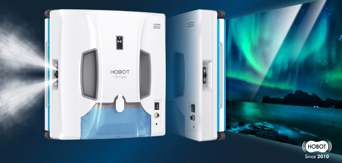 Na obrazie widoczny jest biały robot do mycia okien z napisem \'HOBOT iScraper\', z którego wydobywa się mgiełka. W tle widać zorzę polarną oraz logo \'HOBOT Since 2010\'.
