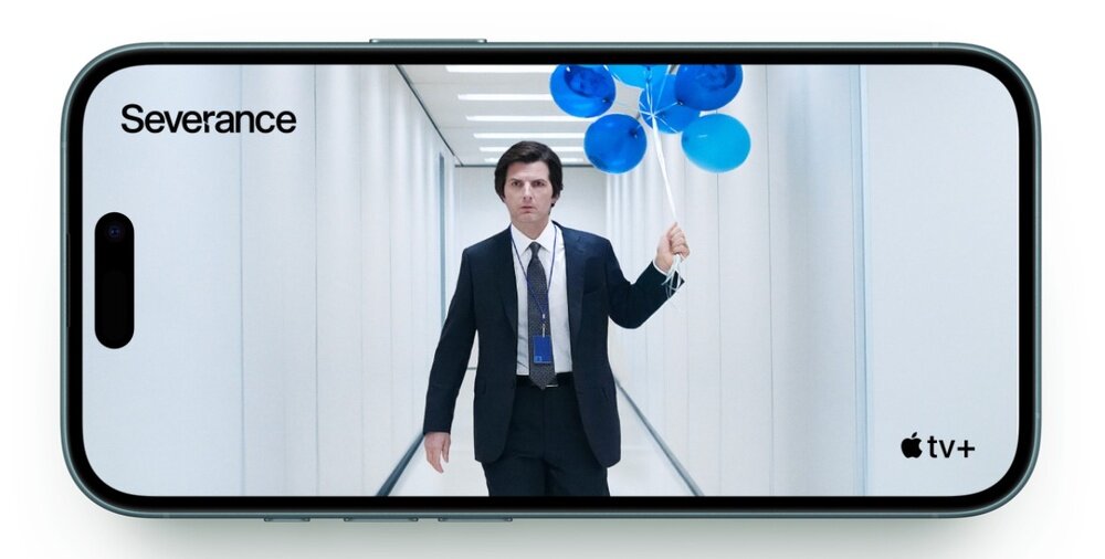 Smartfon wyświetla obraz mężczyzny w garniturze trzymającego niebieskie balony, stojącego w jasnym korytarzu. Na ekranie widoczne są napisy \'Severance\' i \'apple tv+\'.