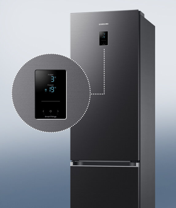 Prosty w obsłudze wyświetlacz zewnętrzny pokazany na zbliżeniu Grafitowa lodówka z wyświetlaczem pokazującym temperaturę: Fridge 3°C, Freezer -19°C. Na wyświetlaczu widoczne jest logo \'SmartThings\'.