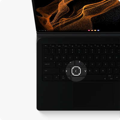 phpybudqf ergonomic-designfor-easy-typing Czarna klawiatura z podświetlonym klawiszem \'C\' oraz fragment ekranu z abstrakcyjnym, pomarańczowym wzorem.
