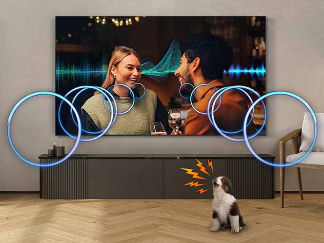 Na ścianie wisi duży telewizor, na którym wyświetlany jest obraz dwóch osób rozmawiających w przytulnym wnętrzu. Przed telewizorem stoi pies, a wokół niego widoczne są graficzne elementy symbolizujące dźwięk.