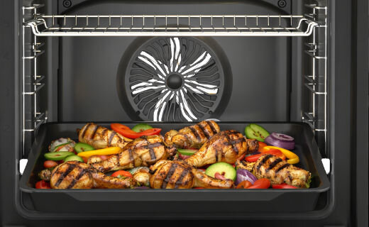 Wnętrze piekarnika z grillem, na którym znajdują się grillowane kawałki mięsa oraz pokrojone warzywa. W tle widoczny jest wentylator piekarnika.