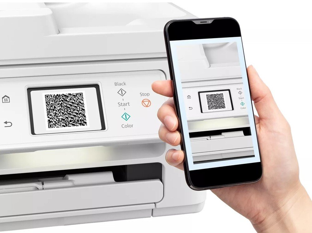 Na obrazie widoczny jest panel sterowania urządzenia wielofunkcyjnego z wyświetlaczem pokazującym kod QR oraz ręka trzymająca smartfon z ekranem pokazującym ten sam panel. Na panelu znajdują się przyciski z oznaczeniami: Black, Start, Stop, Color.