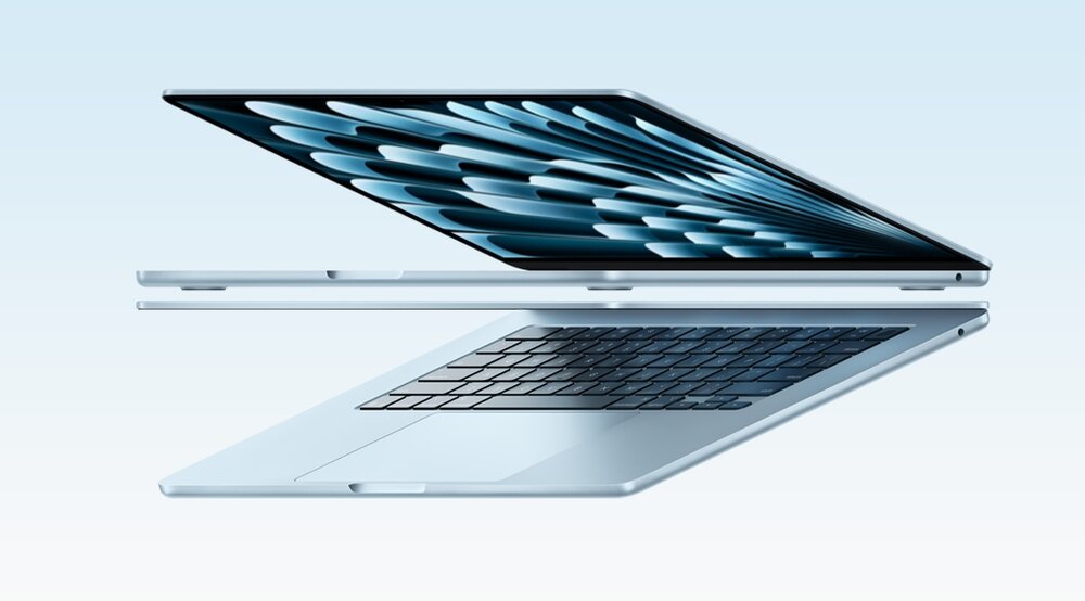 Dwa laptopy w kolorze srebrnym, ustawione w pozycji otwartej, z widocznymi klawiaturami i ekranami. Na ekranach widoczny jest abstrakcyjny wzór w odcieniach niebieskiego.