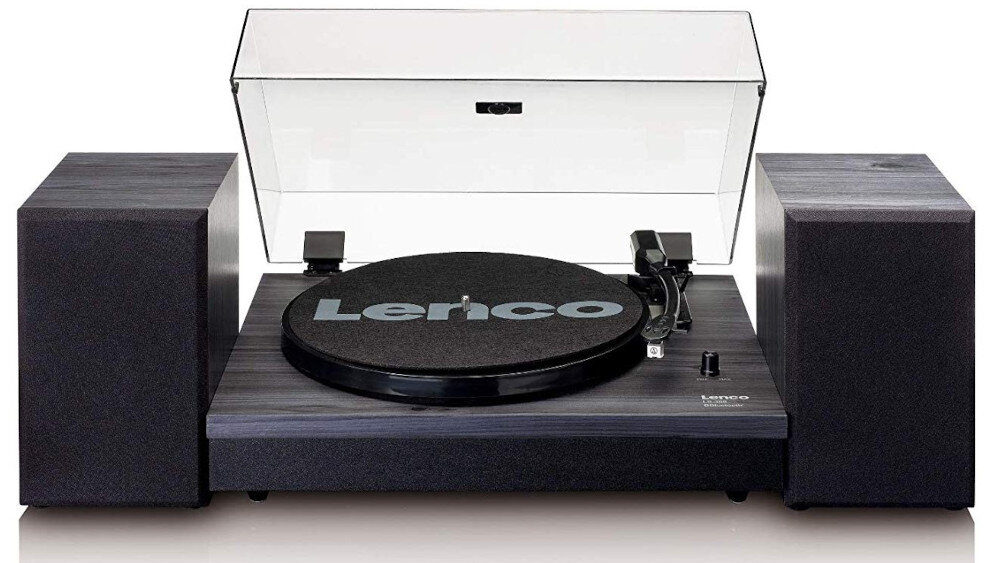 Gramofon z czarną obudową i przezroczystą pokrywą, z widocznym logo \'Lenco\' na talerzu. Po bokach znajdują się dwa głośniki w ciemnym kolorze.