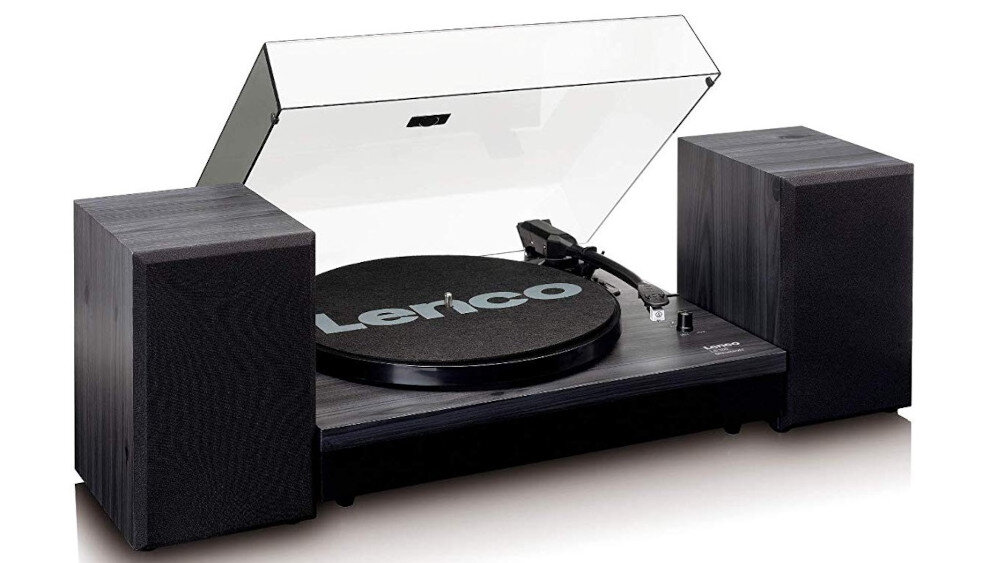 Czarny gramofon z przezroczystą pokrywą, na której widoczny jest napis \'Lenco\'. Po obu stronach gramofonu znajdują się dwa głośniki.
