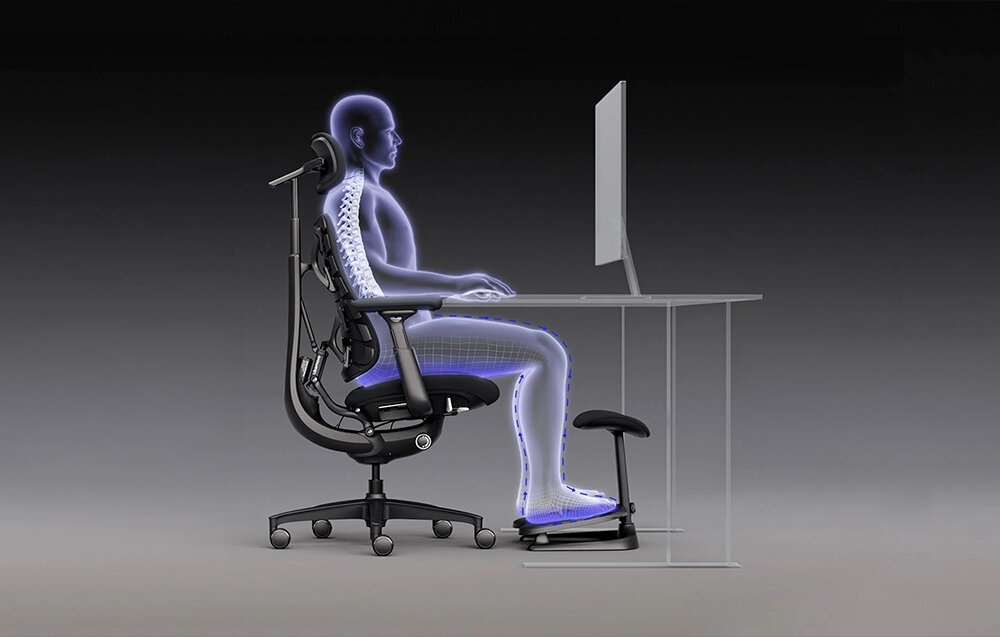 Obraz przedstawia sylwetkę osoby siedzącej na ergonomicznym krześle przy biurku, z nogami opartymi na podnóżku. Sylwetka jest podświetlona, co podkreśla postawę ciała i ułożenie kręgosłupa.