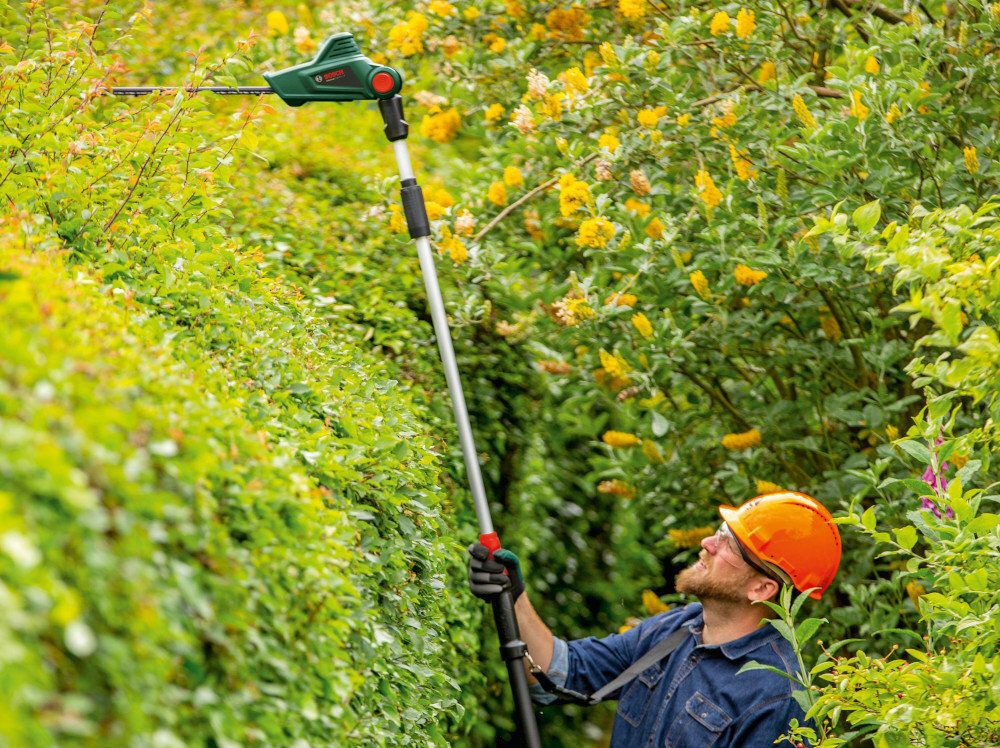 Nożyce do żywopłotu BOSCH UniversalHedgePole 18 akumulatorowe ogród kwiaty żywopłot osoba przycina żywopłot do efektywnej pielęgnacji żywopłotów w ogrodach i przestrzeniach zielonych teleskopowy drążek z regulacją długości obrotowa głowica cięcie gałęzi na wysokości do 2,6 m