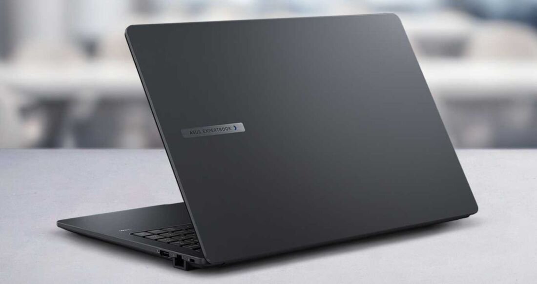 Na obrazie widoczny jest zamknięty laptop w kolorze ciemnoszarym z logo \'ASUS EXPERTBOOK\' na pokrywie. Tło jest rozmyte, co sugeruje, że laptop znajduje się na biurku.