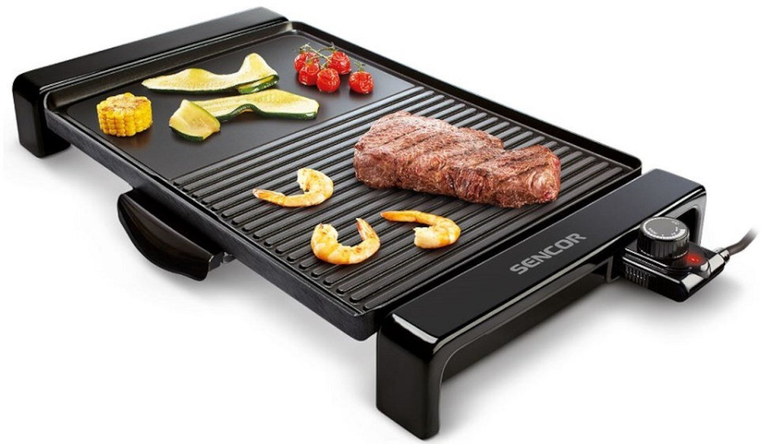 Grill elektryczny z logo SENCOR, na którym znajdują się kawałki mięsa, krewetki, plasterki cukinii, pomidorki koktajlowe i kawałek kukurydzy. Grill posiada czarną powierzchnię z regulatorem temperatury.