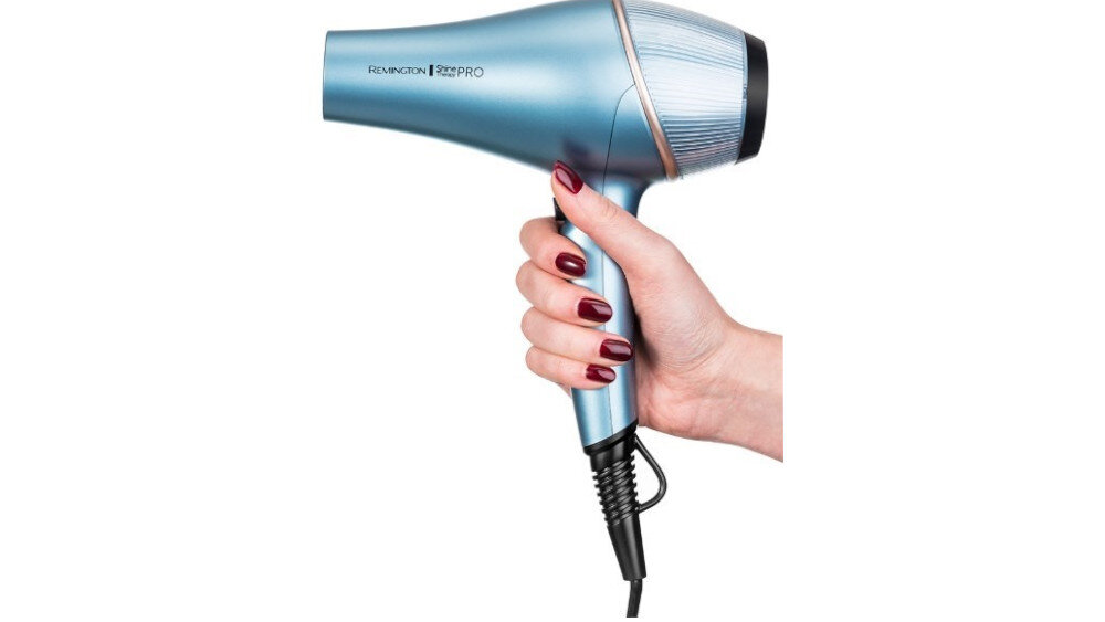 Osoba trzyma niebieską suszarkę do włosów z napisem \'REMINGTON Shine PRO\'.